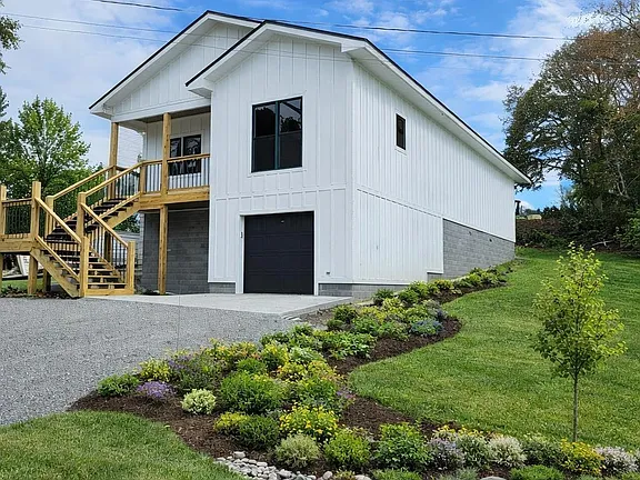 Side view of Stag & Stone showing the white board-and-batten siding and garage
