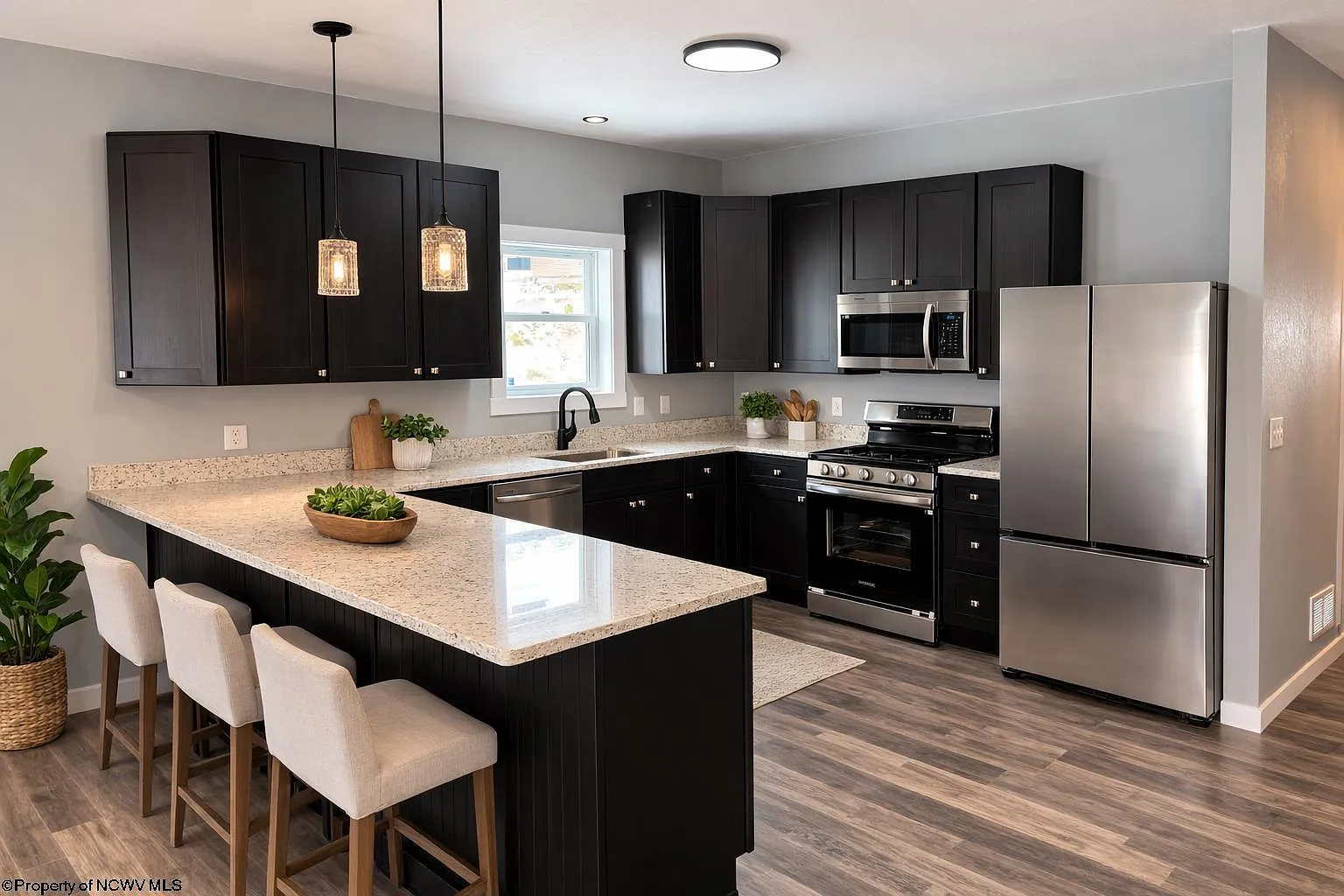 Full kitchen with dark cabinetry, stone countertops and stainless appliances