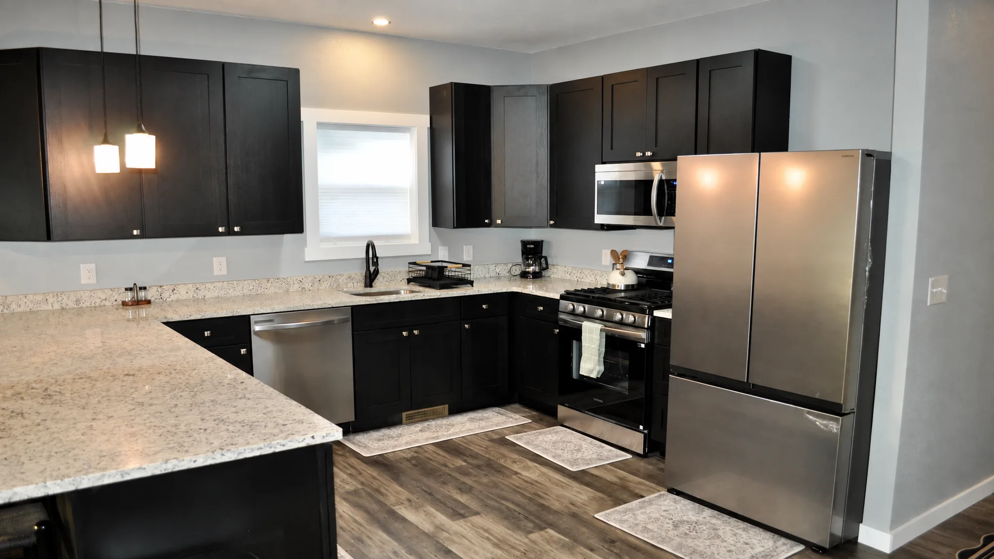 Chef's kitchen with granite counters, black shaker cabinets and stainless appliances